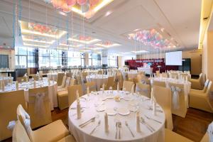 un salón de banquetes con mesas y sillas blancas en Olive Tree Hotel Penang, en Bayan Lepas