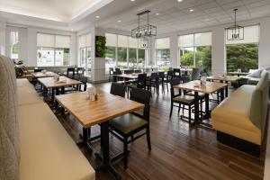 a restaurant with tables and chairs and windows at Hilton Garden Inn State College in State College