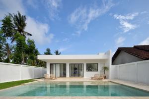 a villa with a swimming pool and a house at Balear Villa in Kuta Lombok