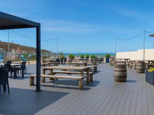 a deck with wooden benches and tables and chairs at 39 Greenlands, Littlesea Holiday Park in Wyke Regis