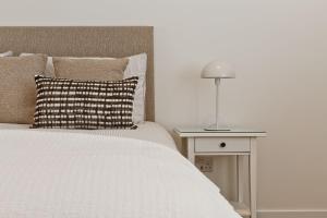 a bedroom with a bed and a table with a lamp at Fellbeck Holiday Home - Cartmel in the Lake District in Cartmel