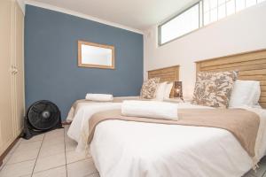 Dos camas en una habitación con paredes azules. en 27 Kyalanga Umhlanga Rocks Beachfront, en Durban