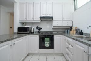 Una cocina blanca con gabinetes blancos y un microondas. en 27 Kyalanga Umhlanga Rocks Beachfront, en Durban 34 fotos más