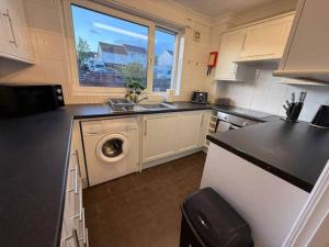 a kitchen with a sink and a washing machine at Modern 2BR Sleeps 4 Central Scotland with Parking in Banknock +13 photos