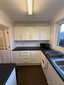 a kitchen with white cabinets and a sink at Modern 2BR Sleeps 4 Central Scotland with Parking in Banknock