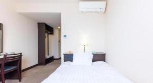 una camera con letto bianco, scrivania e sedia di Tabist Hotel New Osamura Sabae a Fukui