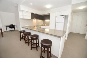 a kitchen with bar stools and a counter with a sink at Curtis Central Apartments Official in Gladstone +135 photos