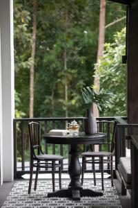 un tavolo nero e sedie su un portico con una pianta di Perana Wellness Resort Chiang Mai a Ban Thung Pong