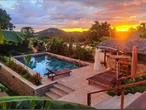 a swimming pool with a bench and an umbrella at Villa MICKA Nosy be in Hell-Ville