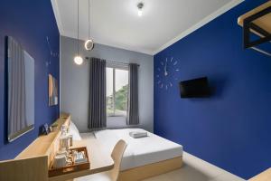a blue room with a bed and a desk and a tv at Cove Stariez in Binong