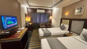 a hotel room with two beds and a flat screen tv at Hotel Dr Rajkumar International in Bengaluru