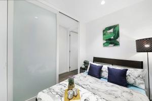 a bedroom with a bed with blue pillows and a table at Bright & Modern 2BR Apt Walk to Central in Melbourne