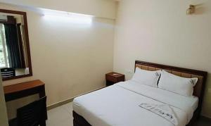 a bedroom with a white bed and a window at FabHotel JK Grand in Cochin