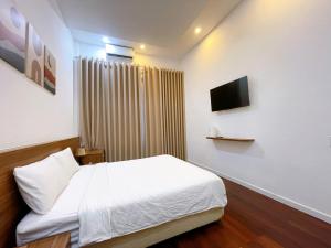 a bedroom with a white bed and a television at Ngoc Toan Retreat in Dong Hoi