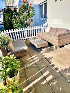 a patio with wicker furniture and plants and a white fence at Stellina Apartment beim Europa Park Rust in Rust +5 photos