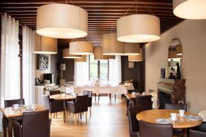 a dining room with tables and chairs and chandeliers at Le Clos De Bourgogne in Moulins