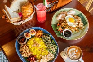 a wooden table with two plates of food on it at The Arca Villas by GenuineHost in Sanur
