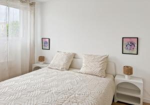 a white bedroom with a bed and two night stands at Le Sunny Side - Appartement pour 4 personnes Disneyland in Montévrain