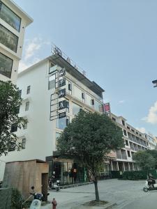 un edificio blanco alto con un árbol delante de él en Ban Shan Du Hotel, en Yangshuo