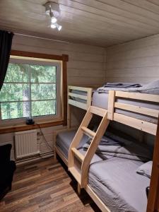Un dormitorio con dos literas y una ventana. en Gemuetliches Blockhaus im Wald, en Auktsjaur