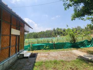a building with a fence in front of a field at Tusker Valley Bamboo Room Mudumalai by Privacy Homes in Mudumalai National Park