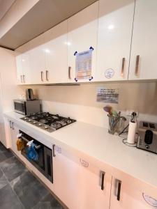 a kitchen with white cabinets and a stove top oven at Mahzan on Dromana Room 3 in Truganina