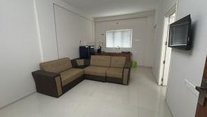 een woonkamer met een bank en een televisie bij Le divines in Guruvāyūr