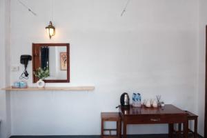 a mirror on a white wall with a wooden desk at Sabaydee Guesthouse in Ban Houayxay