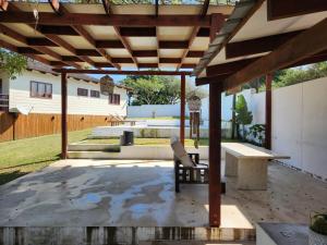 a patio with a bench under a wooden pergola at Ponta Serenity Spot in Lopes