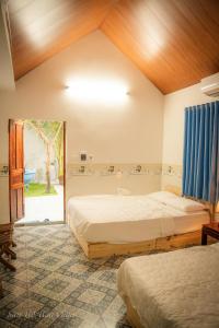 Un dormitorio con dos camas y una ventana en San Hô Hòn Chùa Home, en Mỹ Quang