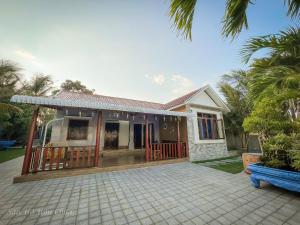una pequeña casa blanca con un banco delante en San Hô Hòn Chùa Home, en Mỹ Quang