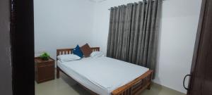 a small bedroom with a bed and a window at Vedic Nirvana Home Stays & Rooms in Irinjālakuda
