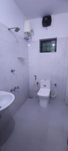a white bathroom with a toilet and a sink at Vedic Nirvana Home Stays & Rooms in Irinjālakuda