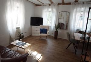 a living room with a tv and a chair and a table at Ferienwohnung Haus Gänseplatz in Volkach