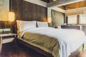 a bedroom with a large bed and a kitchen at Tsingpu Tulou Retreat 青普文化行馆 南靖土楼店 in Nanjing