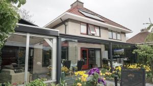 a house with windows and flowers in front of it at Logies Jardin Schagen in Schagen