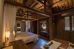 a bedroom with a bed and a table in a room at Tsingpu Tulou Retreat 青普文化行馆 南靖土楼店 in Nanjing