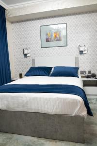 a bedroom with a large bed with blue and white sheets at Prime Suites Hotel in Yerevan