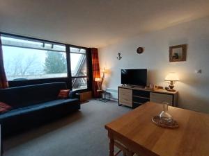 a living room with a couch and a tv and a table at À deux pas des pistes in Aragnouet