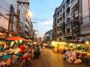 a street with people sitting at tables in a market at Toss Inn Sang Chan - Hat Yai in Hat Yai