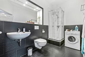 une salle de bain avec un lavabo, des toilettes et une machine à laver dans l'établissement LUXOMES - Modern Design Apartments - Ingolstadt Central, à Ingolstadt 55 autres photos
