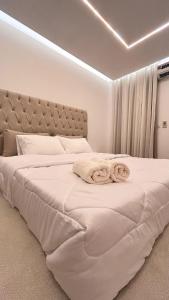 a white bedroom with a large bed with two towels on it at Luxurious and hotel-like accommodation with garden view in New cairo