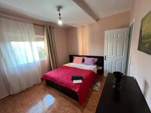 een slaapkamer met een bed met een rode deken en een raam bij Open Door Hostel in Tirana +13 foto's