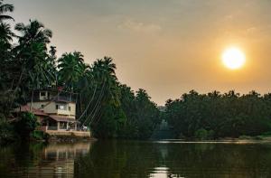 una casa sul fianco di un fiume con alberi di Nadi Teera Homestay a Honāvar
