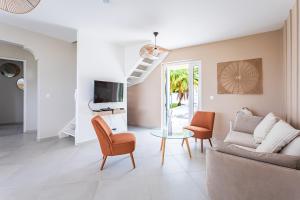 Una sala de estar con un sofá y sillas y un televisor. en Kaz Bel Horizon, vue mer panoramique et piscine privée au Gosier, en Le Gosier