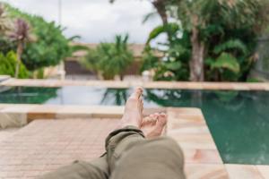 una persona tumbada en un banco con los pies en alto en Le Port Guesthouse, en Mossel Bay