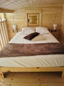 a large bed in a wooden cabin with two lamps at Le chalet des Sarteaux in Ville-sur-Lumes
