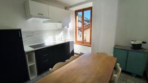 a kitchen with a wooden table and some chairs at BLACK DOLOMYTE Apartment in Schilpario