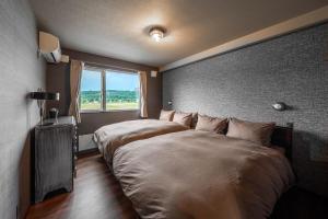two beds in a room with a window at The Horizon Residence in Makubetsu