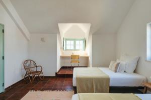 ein Schlafzimmer mit einem Bett, einem Tisch und einem Stuhl in der Unterkunft Charneca Caparica Casa Rey by Hopstays in Vale de Cavalos